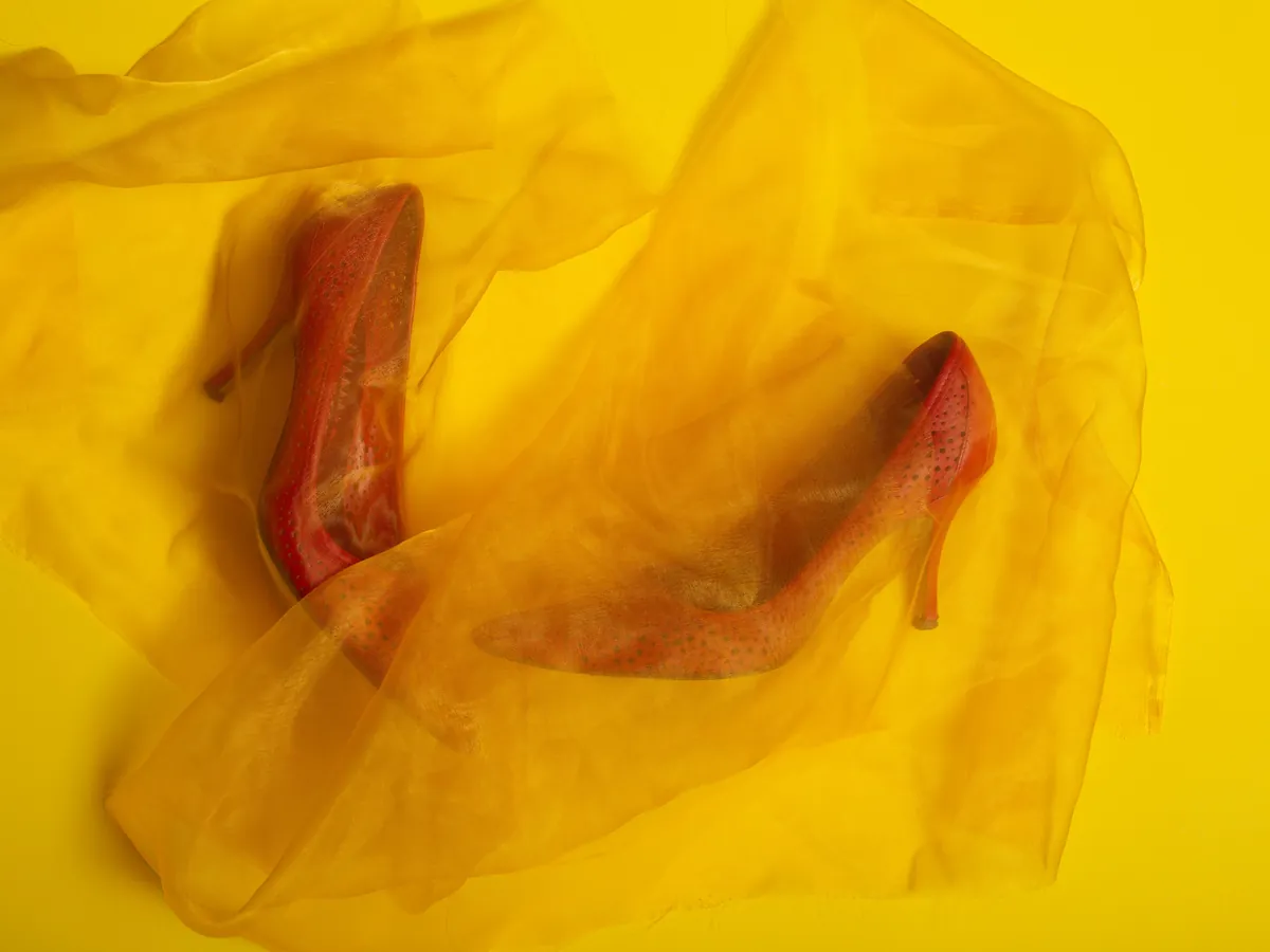 Red heels wrapped in yellow organza on a yellow backdrop